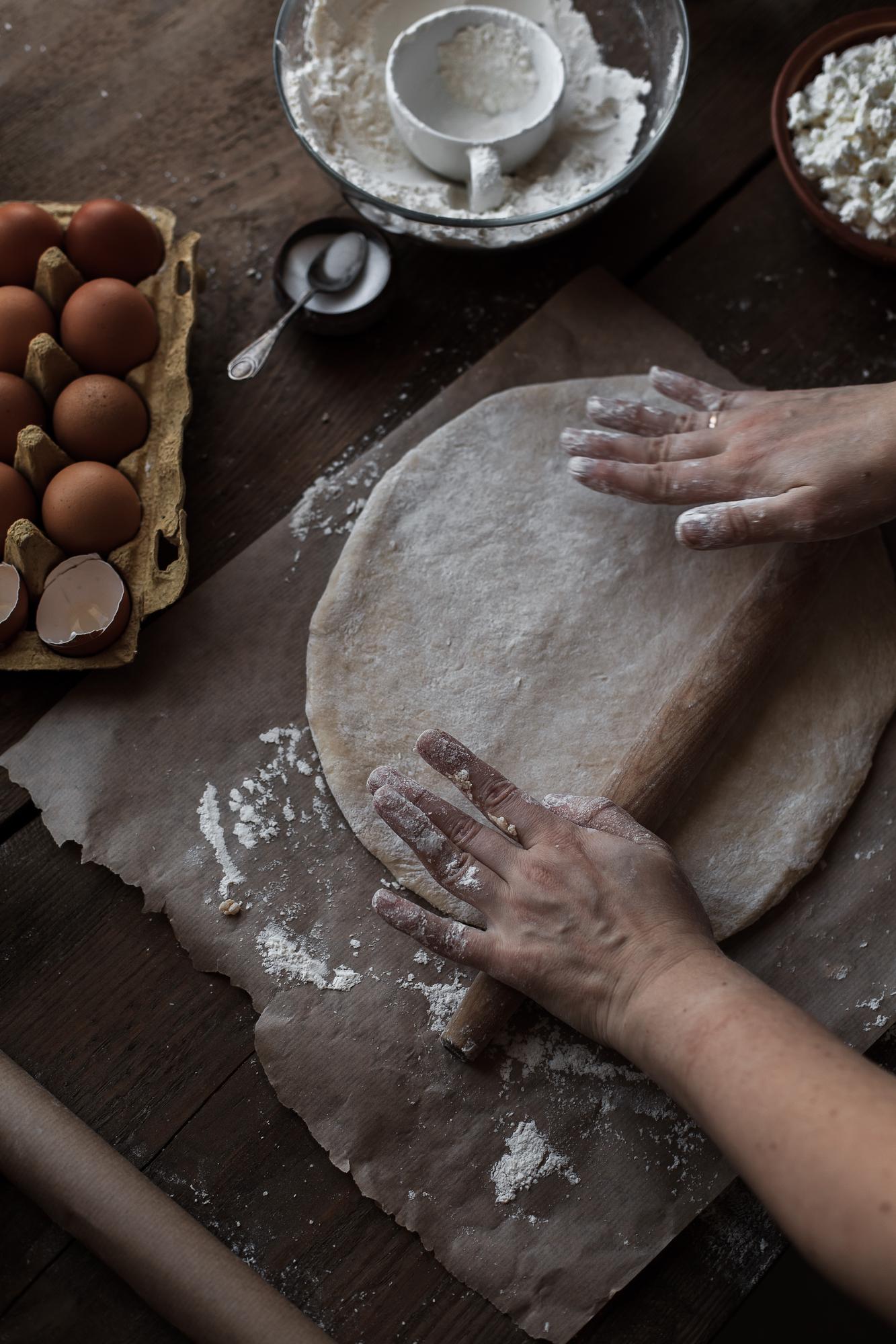 Hands preparing dough on wooden table